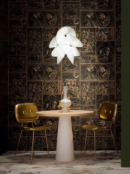 The Serpentine Light is presented against a dark, ornate wallpaper, its bright white form creating a striking contrast and highlighting its intricate twists and turns.