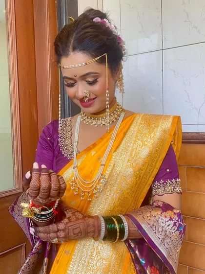 A lovely Marathi bride holding a traditional coconut, a key part of the wedding rituals. Her makeup is soft and glowing, perfect for the ceremony.