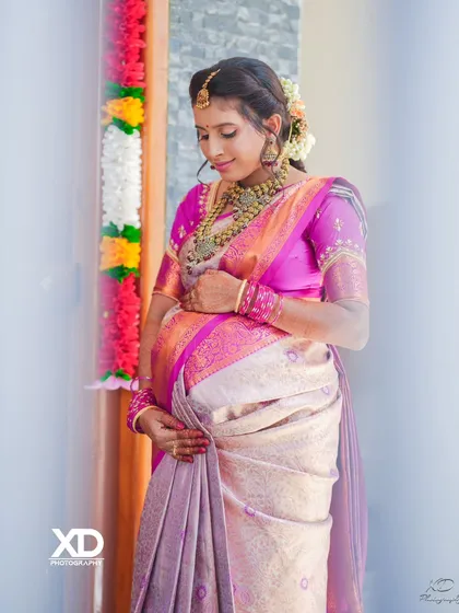 A close-up shot of the expectant mother during her baby shower, her gentle smile and downward glance conveying a sense of peace and happiness.