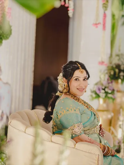 A candid, over-the-shoulder smile. The makeup is soft and natural, highlighting her happiness and the beautiful floral details in her hair.