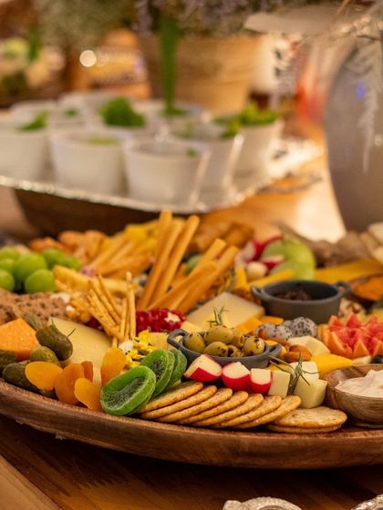 A close-up of a beautifully arranged grazing platter, featuring a colorful assortment of cheeses, fruits, crackers, and dips. Each element is carefully selected for quality and visual appeal.