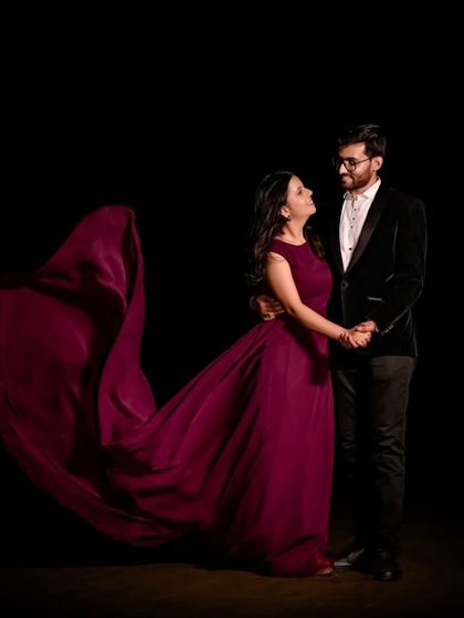 A dramatic pose with a flowing gown. The dark studio background makes the wine-colored trail gown pop, creating a high-fashion pre-wedding look.