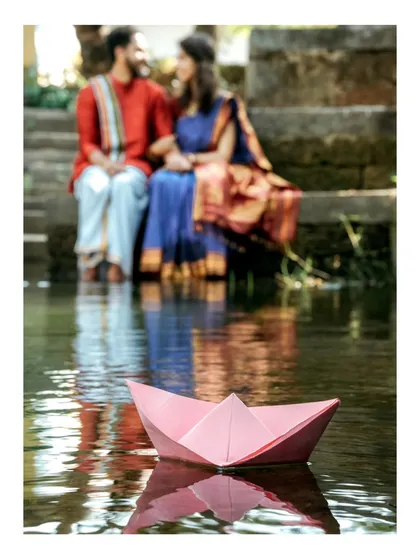 A creative and artistic pre-wedding photo. Using elements like this simple paper boat, I aim to tell a visual story of the couple's journey, set against the calm waters of a traditional temple pond.