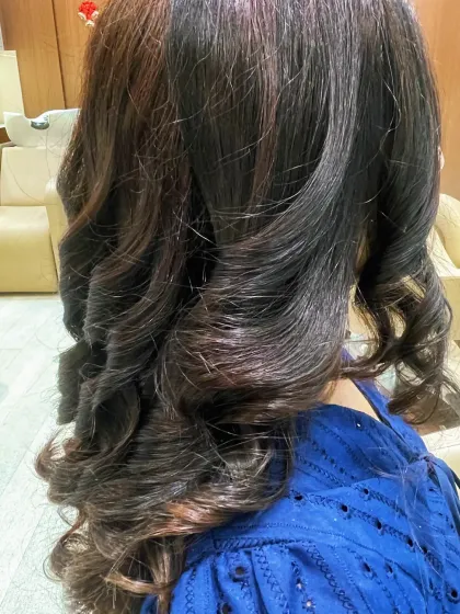A side view of these gorgeous, bouncy curls. The styling enhances the subtle color variations in the hair.