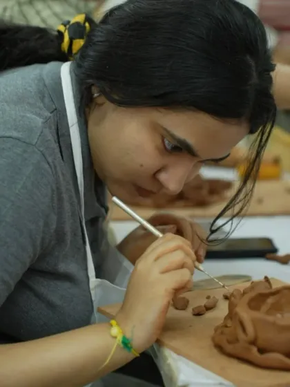 A participant meticulously carves details into her clay creation. The workshop allows for a high degree of personalization and creativity.