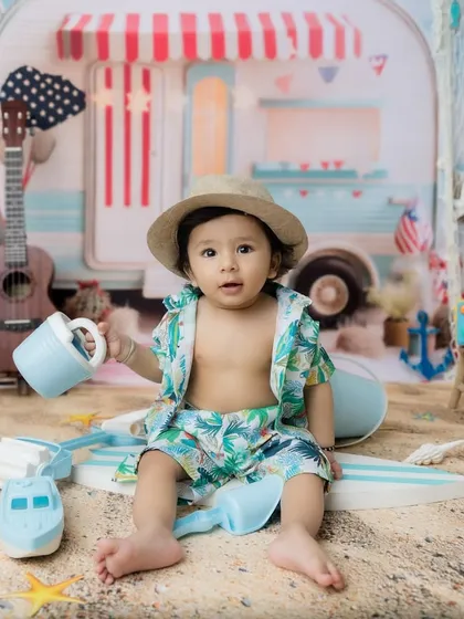 The perfect setup for a summer-themed milestone, with a camper van, ukulele, and sandy floor.