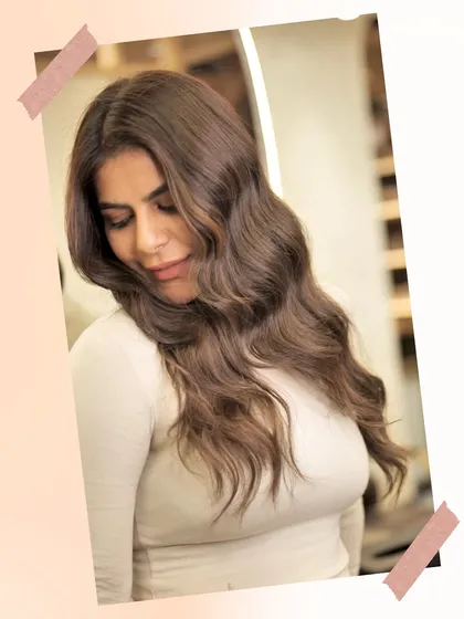 A client admiring her new chocolate brown hair with subtle highlights. The soft waves and rich colour give her a glamorous and sophisticated look.