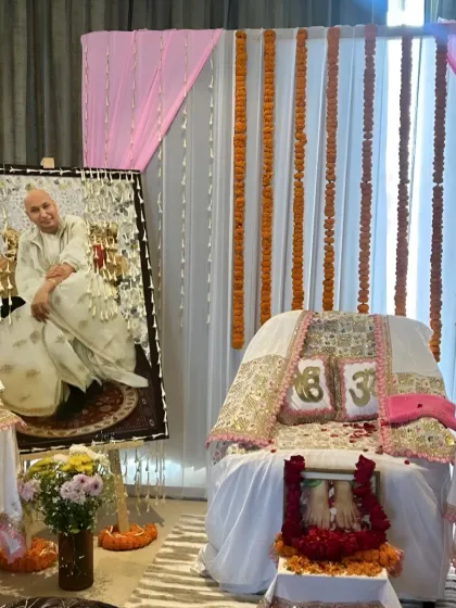 A serene and respectful setup for a 'Jai Guruji' Satsang. I used white and pink drapes, marigold garlands, and a beautifully decorated seat for the Guru's portrait.