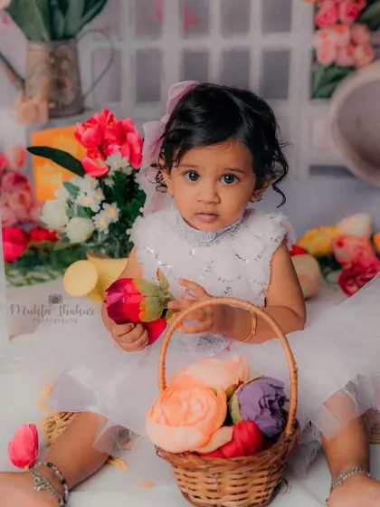 Innocence at its best. This little girl is sitting in a garden of flowers, celebrating her very first birthday.