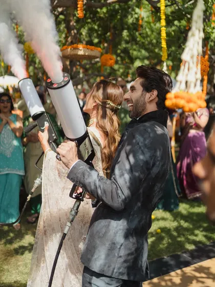 Let's make it fun! The couple makes a memorable entrance at their Mehendi party using color smoke guns, adding a modern and playful twist to the celebration.