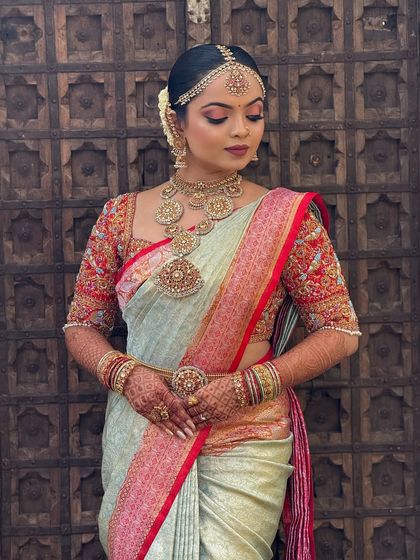 A full portrait of the bride against a traditional wooden door. The makeup is classic and elegant, perfectly suiting the timeless backdrop.