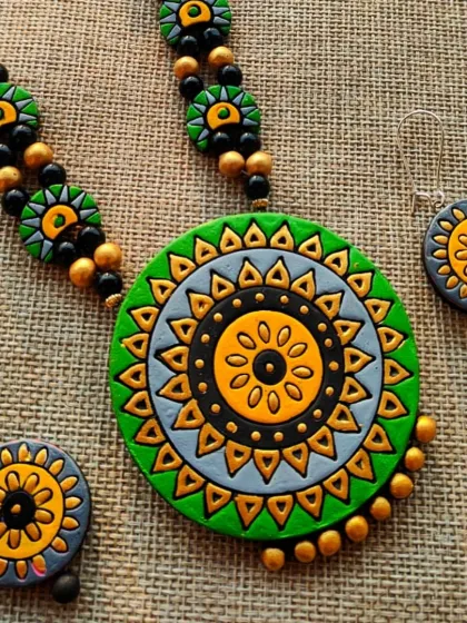 A close-up of the green mandala 'haram' style necklace, showing the intricate patterns on the pendant and earrings.
