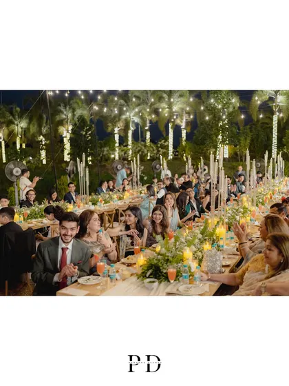Guests enjoying the intimate dinner party. The long-table setup encourages conversation and creates a warm, communal atmosphere.