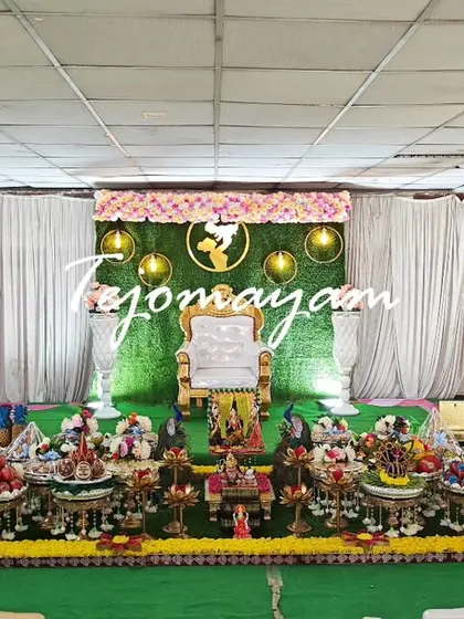 A baby shower setup in a simple hall, transformed by the elaborate and traditional plate decoration. The green backdrop adds a touch of nature.