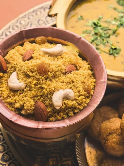 A close-up of Dal Bati Churma, a cornerstone of Rajasthani cuisine. We prepare this dish with authentic techniques, offering the perfect balance of savory dal, baked bati, and sweet churma.