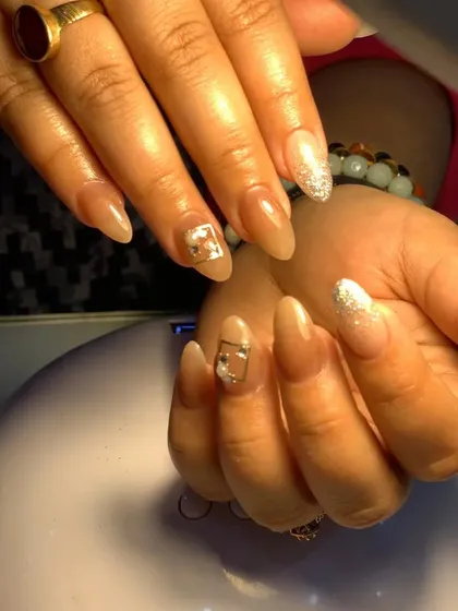 An elegant nude set with silver glitter accent nails and small, delicate charm details.