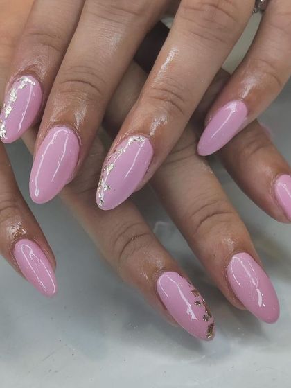 A simple yet elegant set of pink almond-shaped nails, with a subtle accent of crushed gold foil on a few nails.