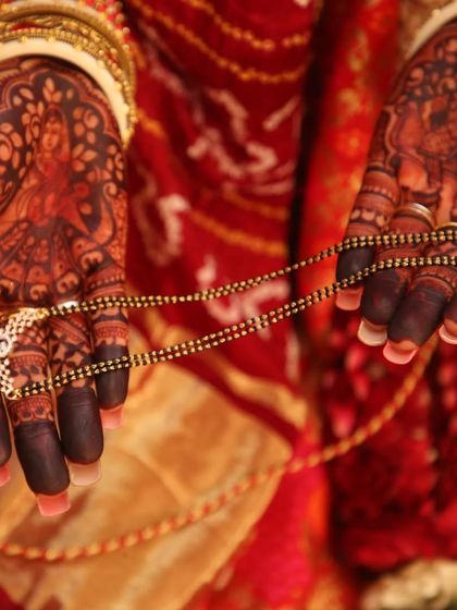 A symbolic shot of a bride holding her mangalsutra. The focus on her hands highlights the deep, dark color of her bridal mehndi.