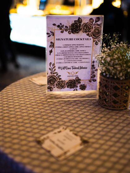 A beautifully designed signature cocktail menu that matches the event's rustic and floral decor. The menu features unique drinks like a Smoked Apple Martini and a Paan & Rose G&T.
