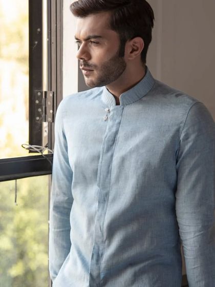 Another view of the pastel blue linen shirt, highlighting its breezy fabric and relaxed yet sophisticated style.