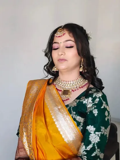 A close-up of the makeup with eyes closed, showing the soft pink eyeshadow and flawless base.