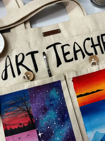 A close-up view of the hand-painted details on the "Art Teacher" tote bag. The bag is made of sturdy canvas and the paintings are sealed with varnish, so the art is durable and can withstand gentle washing.