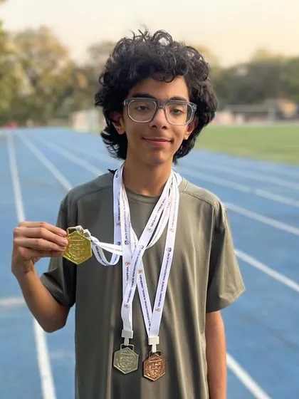 Mahir Thadani showcasing his impressive medal collection from the JBCN International School Sports Day, including a Gold in the 4x200 relay, Silver in 200m, and Bronze in 400m.