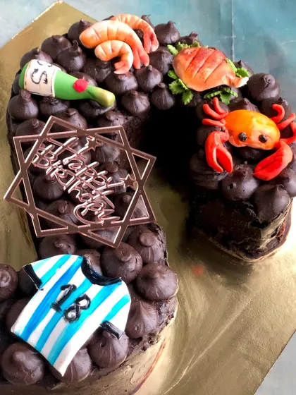 Another view of the 'S' monogram cake, showing the details of the seafood, soccer jersey, and champagne bottle toppers.