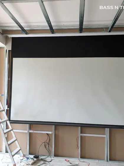 A big screen experience doesn't have to mean a permanent black rectangle on your wall. This image shows the installation of a retractable 4K projector screen, which disappears into the ceiling when not in use, offering a cinematic experience without compromising the room's design.