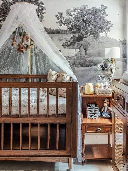 A nursery can be both calming and full of character. In this corner, I paired a classic wooden crib with a delicate canopy and a matching changing table. The monochrome landscape wallpaper creates a serene backdrop for a peaceful sleep.