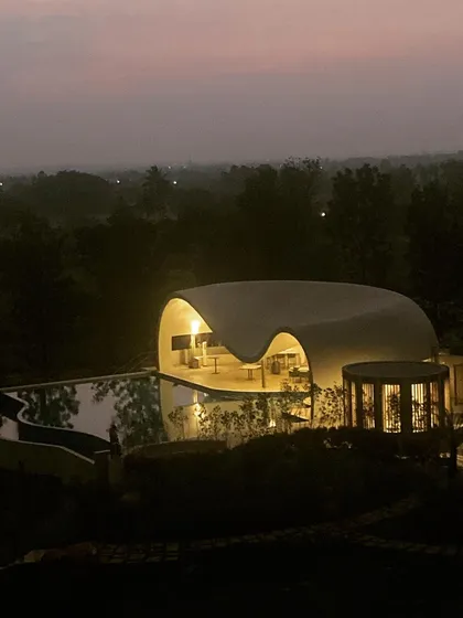 An aerial view of the Aqua Pool & Spa at dusk, showing how the structure glows like a lantern in the Nandi valley, a serene beacon nestled among the trees.