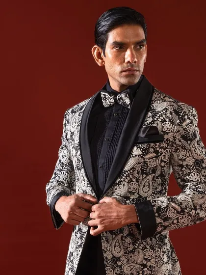 The details make the design. This close-up view reveals the intricate paisley pattern and the flawless construction of one of our custom-made tuxedo jackets, complete with a shawl collar and a perfectly matched bow tie for a truly cohesive and luxurious look.