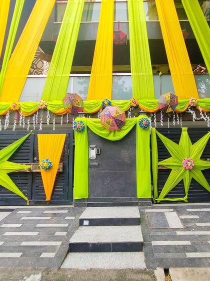 A fresh and vibrant theme using lime green and yellow drapes for a house front, perfect for a daytime summer wedding function.