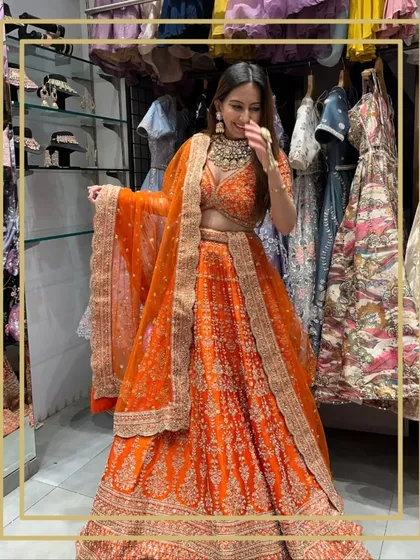 A client having fun trying on a vibrant orange lehenga in my store. The joy of dress-up is for everyone.