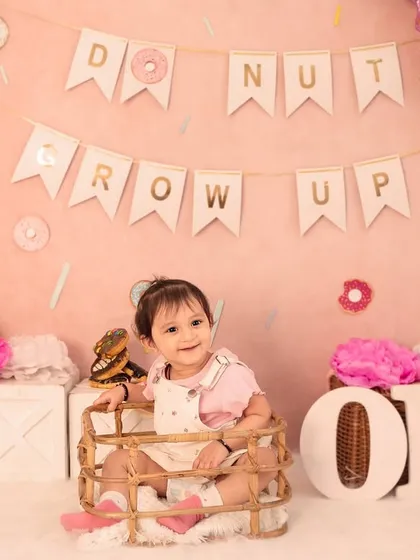 A sweet smile from inside a basket, surrounded by donuts and pink decor. I use various props to create different compositions and keep the baby engaged.
