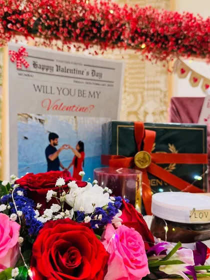 A close-up on the romantic details. The custom 'Will You Be My Valentine?' newspaper, fresh red roses, and a jar of Nutella labeled 'LOVE' come together to create a sweet and memorable moment.
