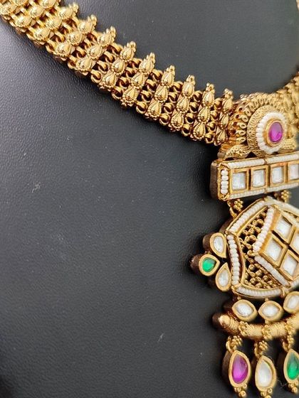 A close-up of the necklace, highlighting the intricate pendant and the colorful stones.