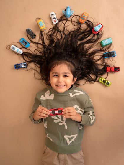 A creative portrait with cars in her hair, showing off her long locks one last time before her first haircut. This was a fun way to personalize her session.