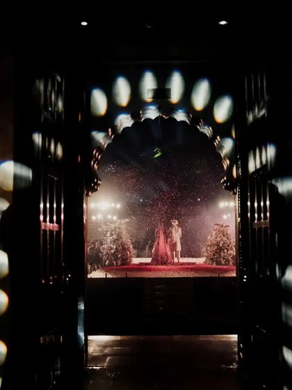 A view from an archway of the couple's varmala, framed by dramatic lighting. We use the unique architecture of destination venues to create cinematic shots.