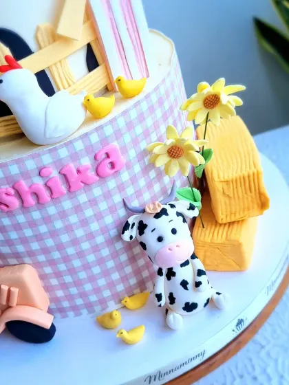 A close-up of the cute fondant cow, chicken, and tractor on the farm-themed cake.