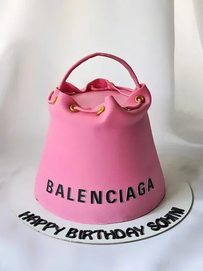 A stylish and modern Balenciaga handbag cake. This sculpted cake is a replica of their iconic bucket bag, perfect for a fashion lover's birthday.
