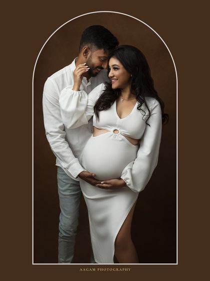 Framed within a soft arch, this couple's portrait feels like a window into a private, loving moment. The white outfits create a clean and modern aesthetic.