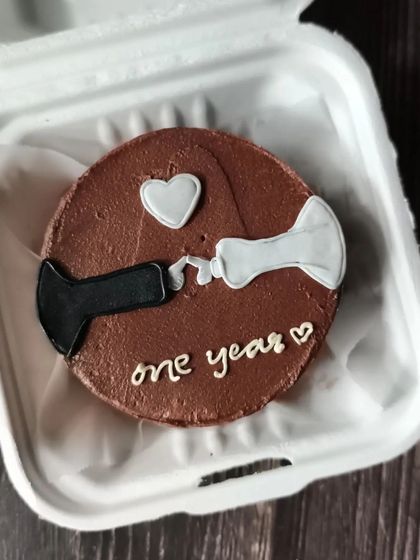 A minimalist and modern anniversary cake. This chocolate bento features a clever design of two toothpaste tubes squeezing out a heart to celebrate a one-year milestone.
