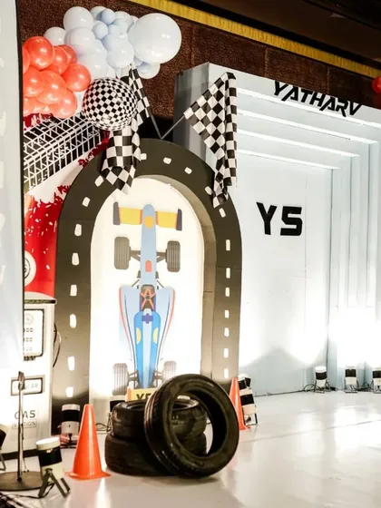 We transformed the space into a high-octane race track for a little hero's 5th birthday. This setup features a custom race car photo booth, track-style flooring, and checkered flag details, showing how we bring high-energy themes to life with complete immersion.