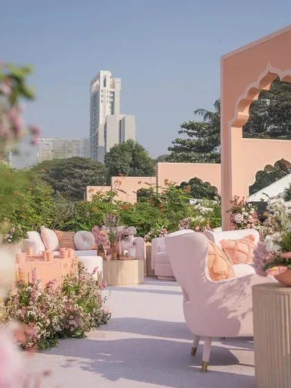 A view through the flowers shows the elegant seating arrangements set against the backdrop of the city and the custom-designed arches.