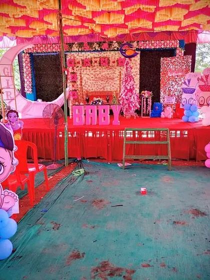 A baby shower stage setup with a moon prop, decorated swing, and cute baby-themed cutouts.