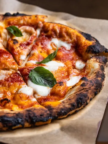 You can never go wrong with a classic, the kind that wraps around you like an old, distant memory. This is our Margherita pizza, with its perfectly charred crust, rich tomato sauce, and fresh basil. It’s the quiet joy of your very first slice, remade just for you.