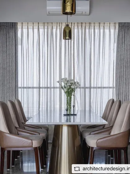 Another view of the dining area in 'Aria Residence', highlighting the elegant lines of the furniture and the soft light filtering through the sheer curtains.