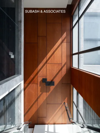 I love using natural light as a design element. Here, sunlight filters through a double-height window, casting dynamic shadows across a wood-paneled wall.