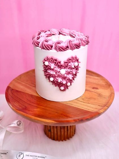A duplicate image of our beautifully piped heart cake, presented on a wooden stand. The detail in the buttercream work makes this a simple but stunning choice.